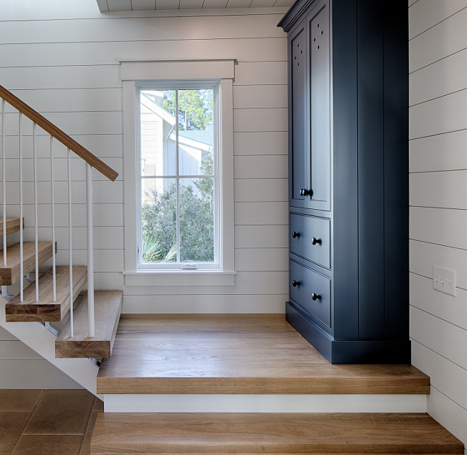 Andes Summit (Benjamin Moore) navy blue paint color on a built-in in an entry of a coastal cottage by Lisa Furey. White oak hardwood floor and stairs in entry with shiplap on walls (Benjamin Moore White OC-151). #andessummit #benjaminmooreandessummit #navybluepaintcolors