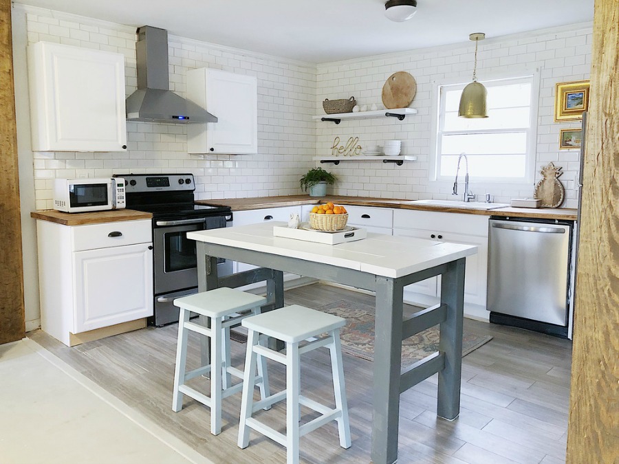 Charming modern farmhouse white kitchen with work table and butcher block counters.