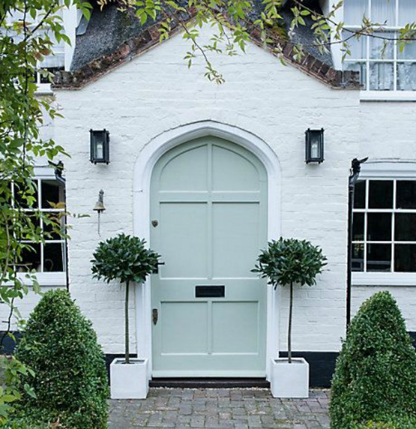 Magnificent white brick house exterior with soft minty green arched front door and pair of bay trees - John Lewis. #whitebrick #housedesign #curbappeal #houseexteriors