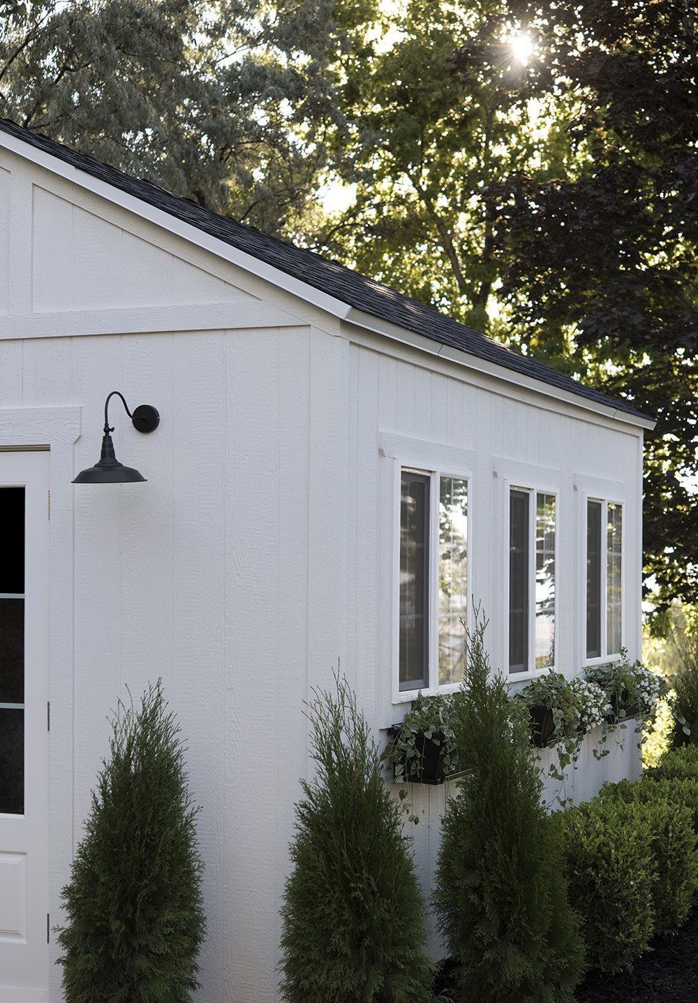 Nuance (Sherwin Williams) is name of white paint on this shed exterior with windows and window boxes - RoomforTuesday. #nurance #whitepaintcolors #exteriorcolors
