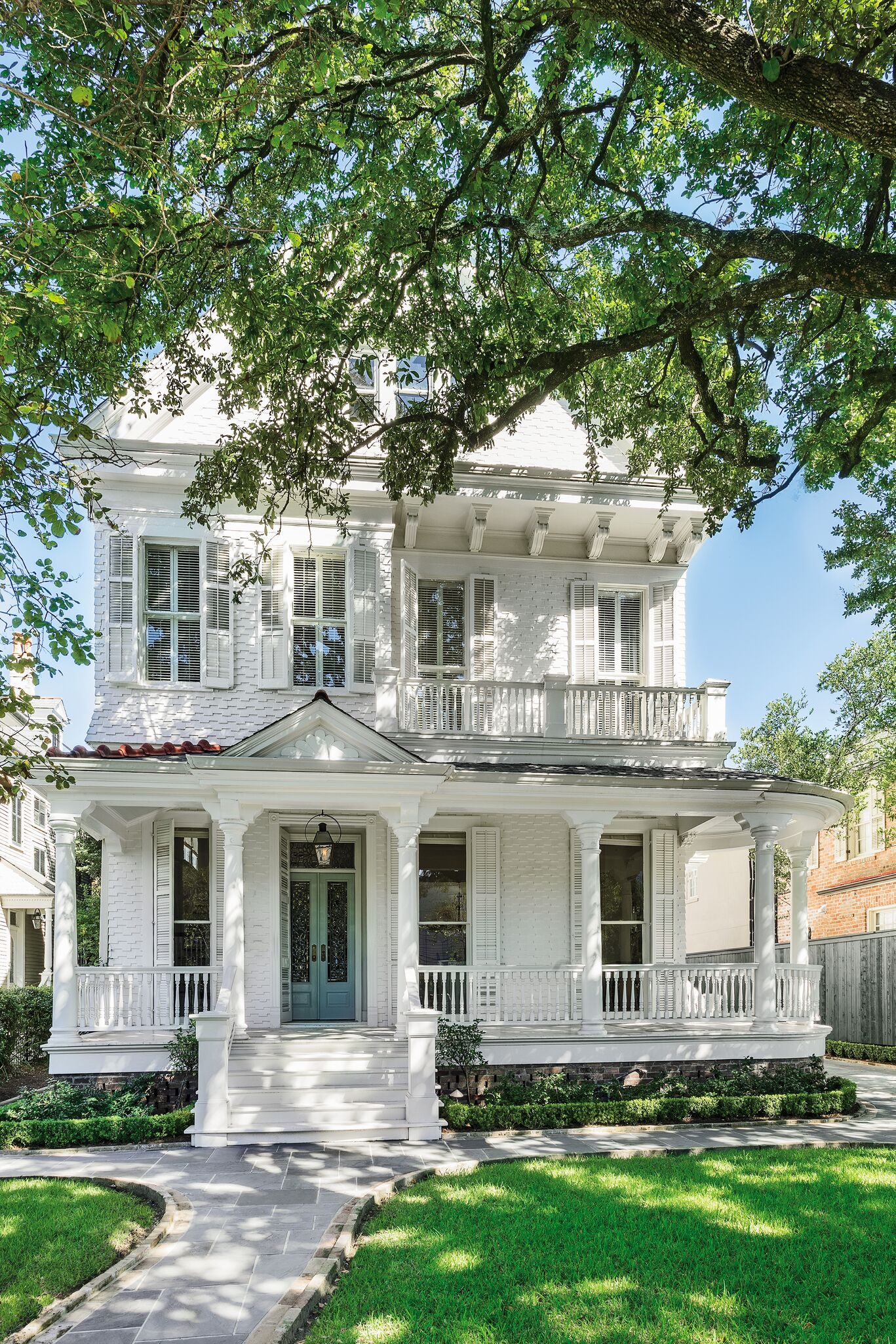 Stately white painted Victorian home has breathtaking architecture and curb appeal in the lower Garden District of New Orleans. #houseexterior #victorianhouses #beautifulwhitehouse #historichome #curbappeal #frontporch