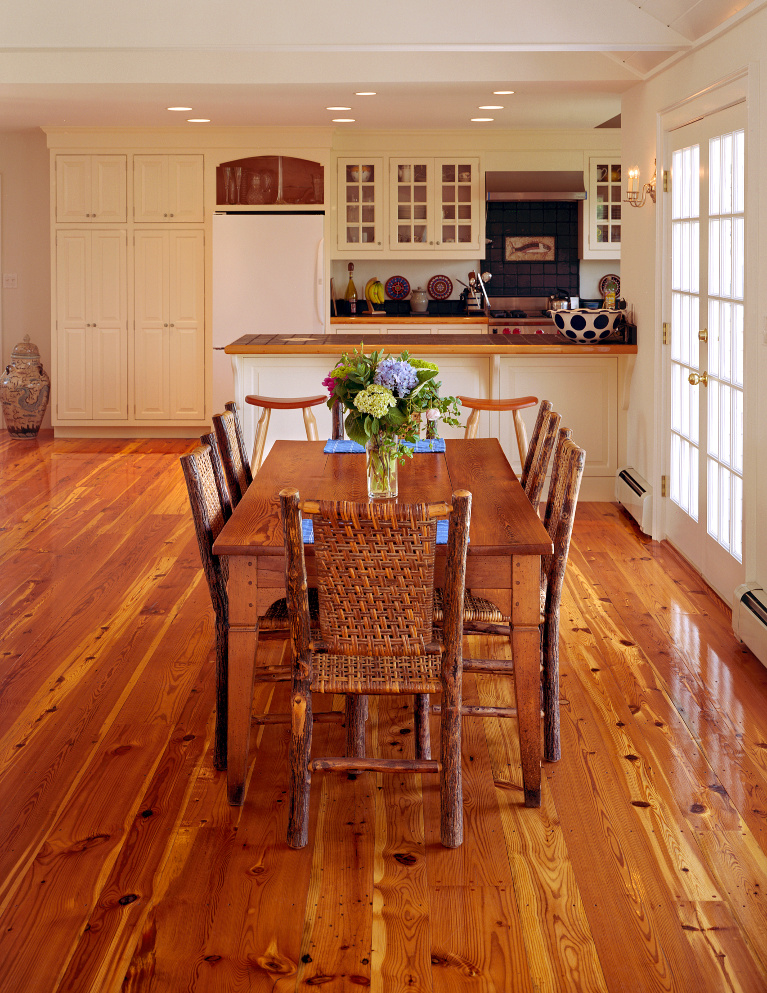 Reclaimed Heart Pine flooring (wide plank by Carlisle) plays a starring role in this casual country breakfast area. adjacent to a white kitchen. #hardwoodflooring #reclaimed #wideplank #flooring #carlisle #heartpine #interiordesign #rusticfloor