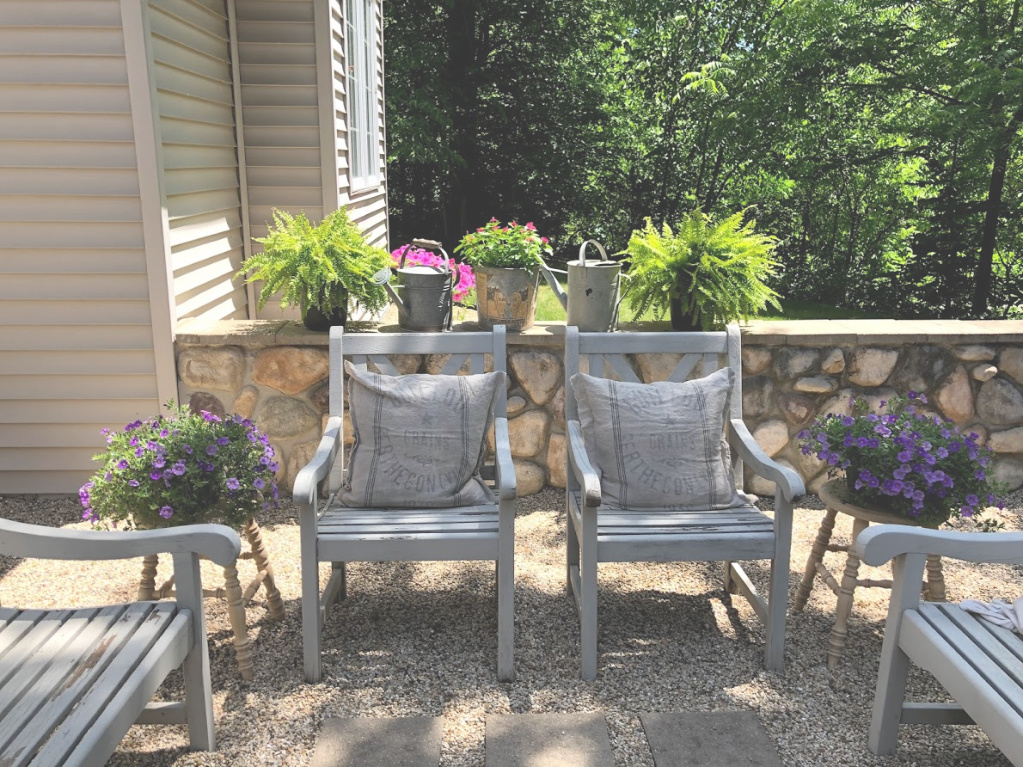 Our French country courtyard in summer with painted wood furniture, grainsack pillows, and pea gravel. #hellolovelystudio #frenchcountry #courtyard #garden #outdoorliving #summer