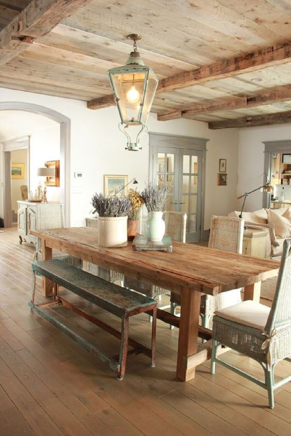 Rustic elegance and uncluttered country decor sing in a French Nordic Farmhouse dining room with knotty wood ceiling and antique lantern. See more European inspired country decor in the story. #FrenchCountry #FrenchNordic #countrydecor 