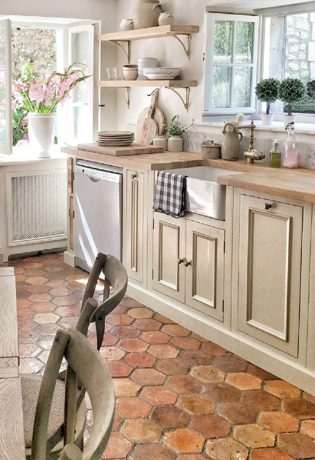 French kitchen with open shelving, antique pots, topiaries, terracotta hex tile floor and limestone painted cabinets in authentic French farmhouse. Vivi et Margot. #frenchkitchens #frenchfarmhouse