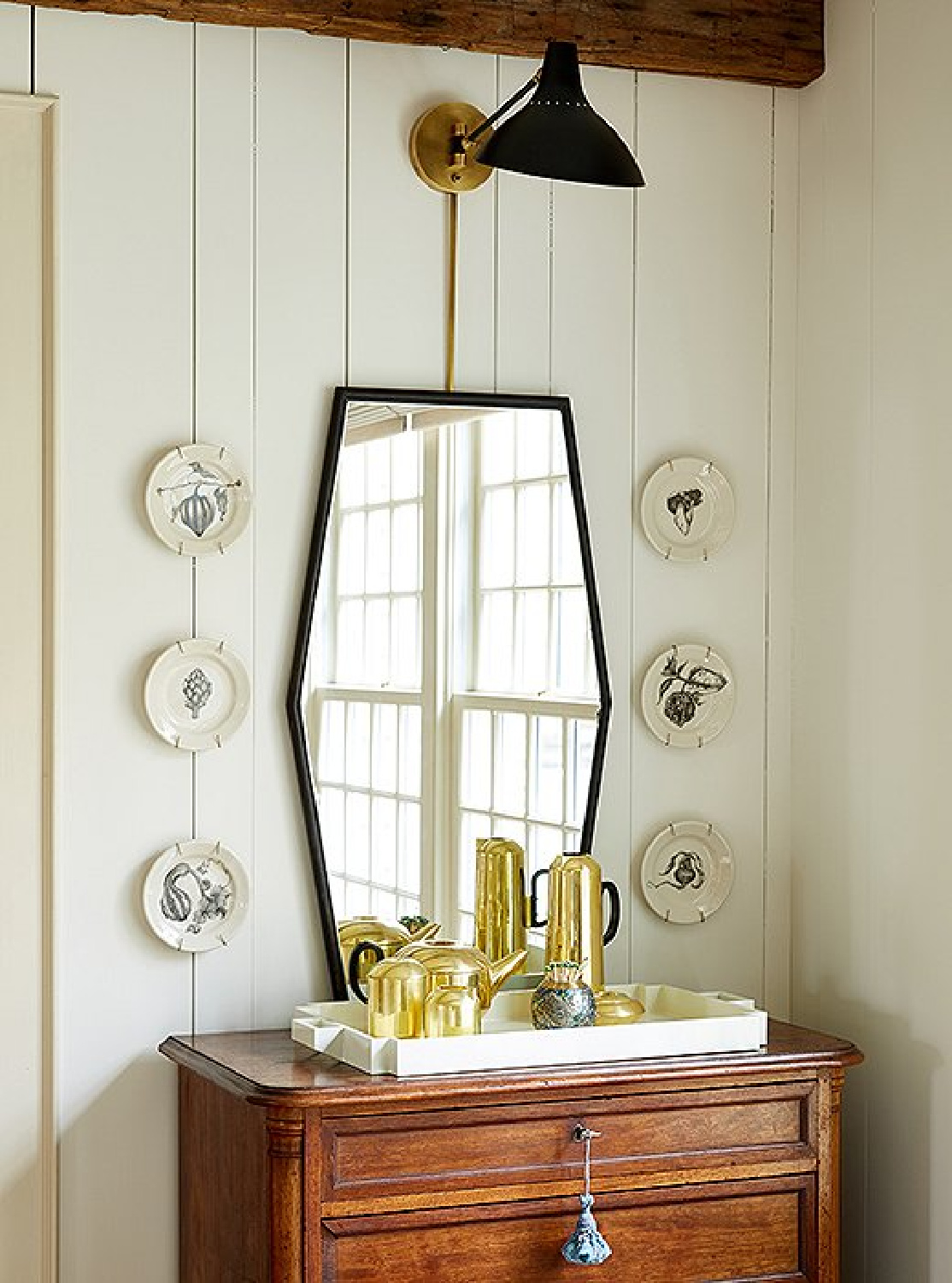 Decorative plates flanking a mirror and sconce in a lovely dining room in an elegant Connecticut farmhouse - OKL.