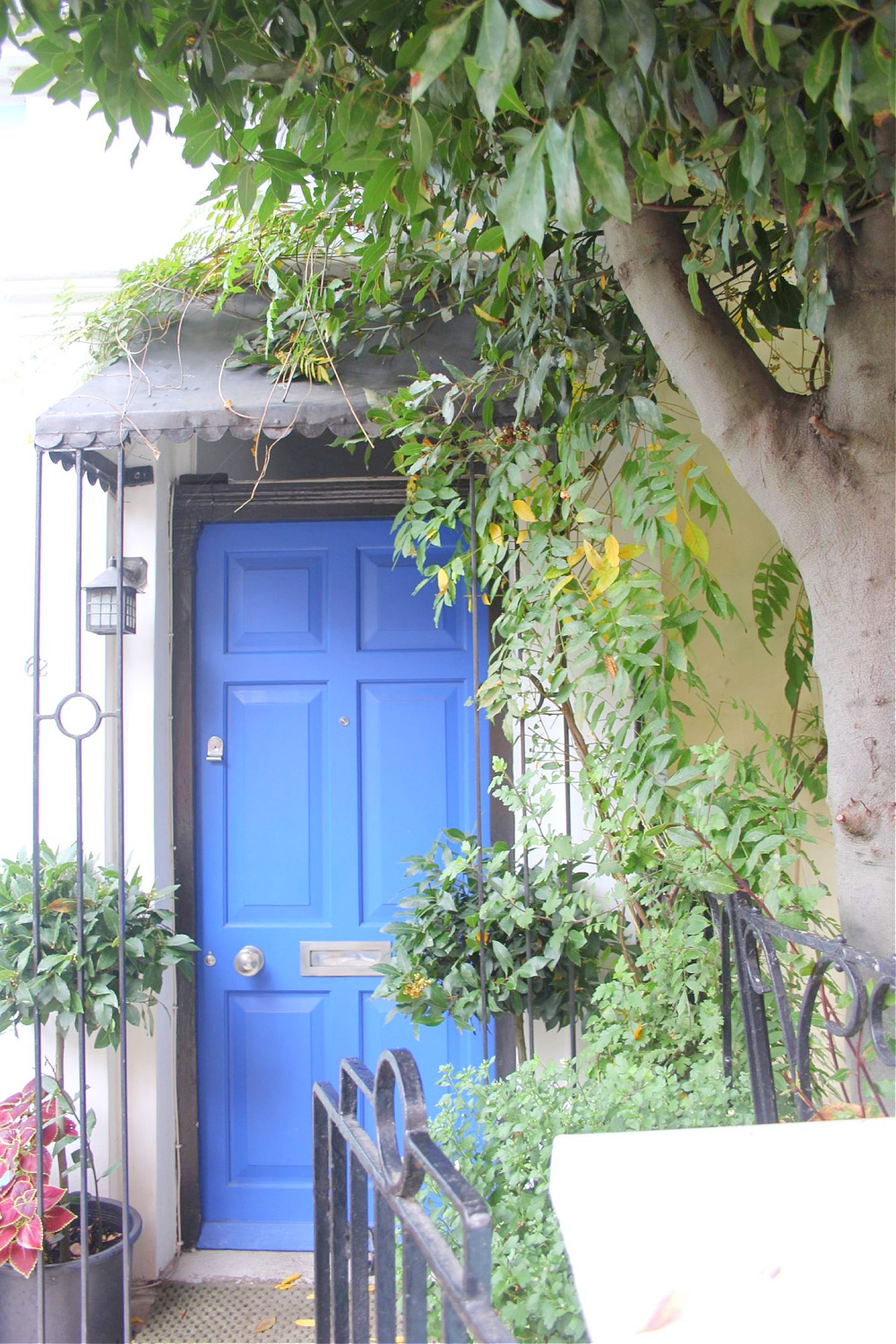 Bold blue door with covered entry in Notting Hill. Come explore paint colors for your front door. #frontdoorcolors #paintcolors #curbappeal