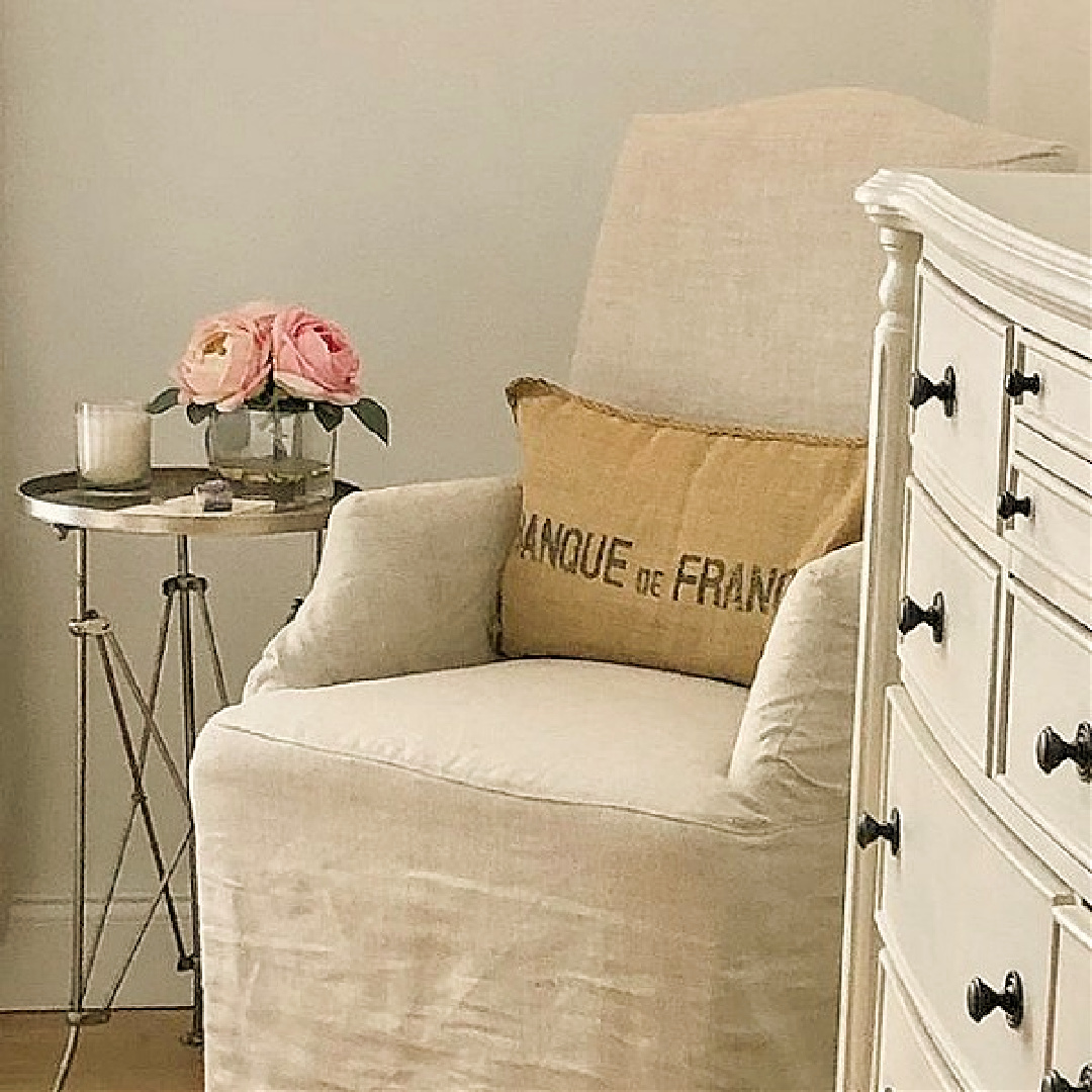 Hello Lovely Studio's Nordic French bedroom with Belgian linen accent chair and campaign style table. #modernfrench #hellolovelystudio #europeancountry