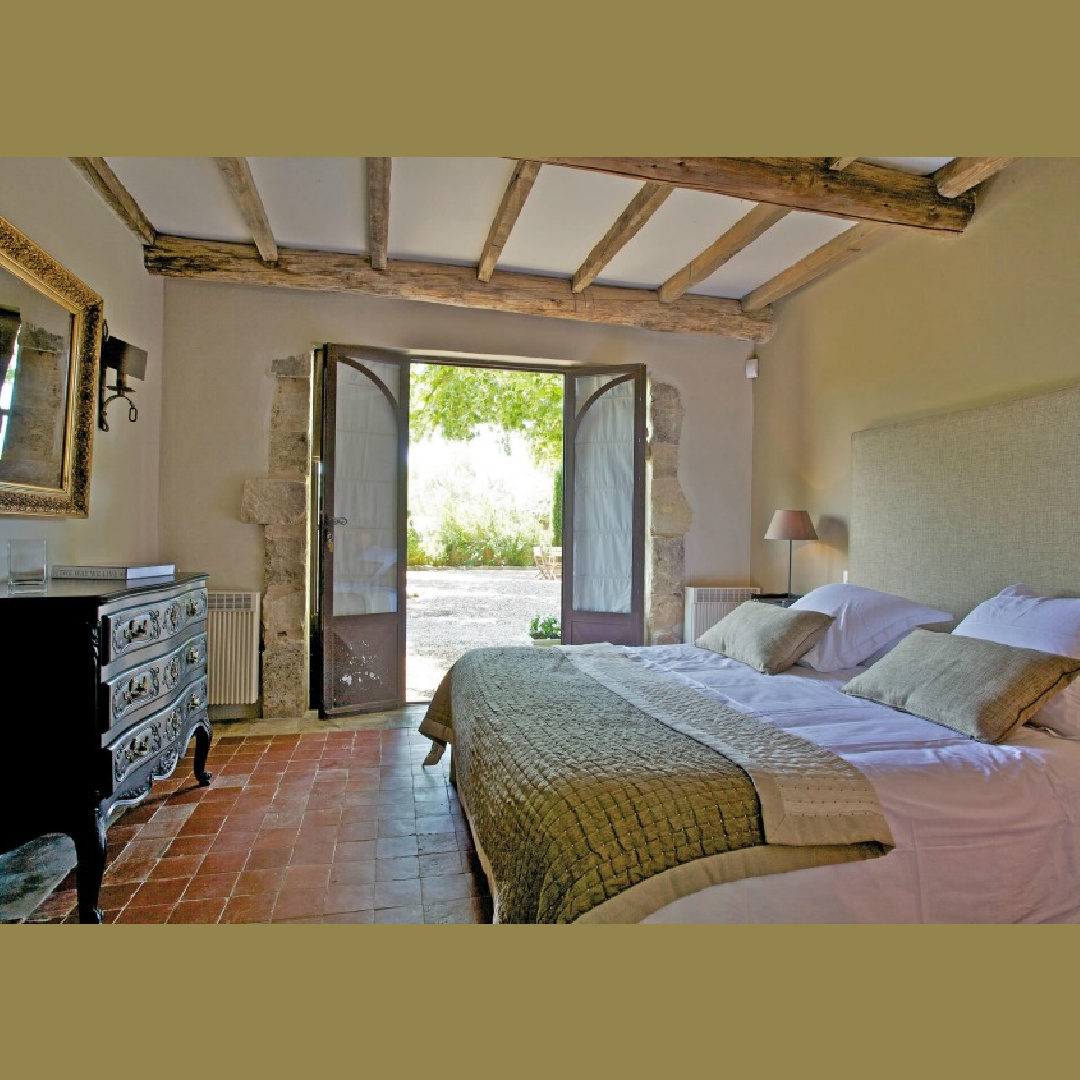 Provence farmhouse bedroom with rustic wood ceiling, stone surrounding French doors, terracotta tile, and elegant antiques - Bonnieux Villa (Your Haven in Paris).