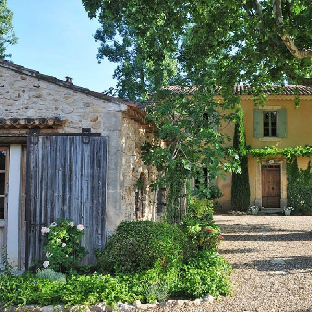 Beautiful French farmhouse exterior with yellow stucco and French blue shutters. Provence vacation rental Bonnieux Villa from Your Haven in Paris with lush gardens, romantic Old World rustic elegance.