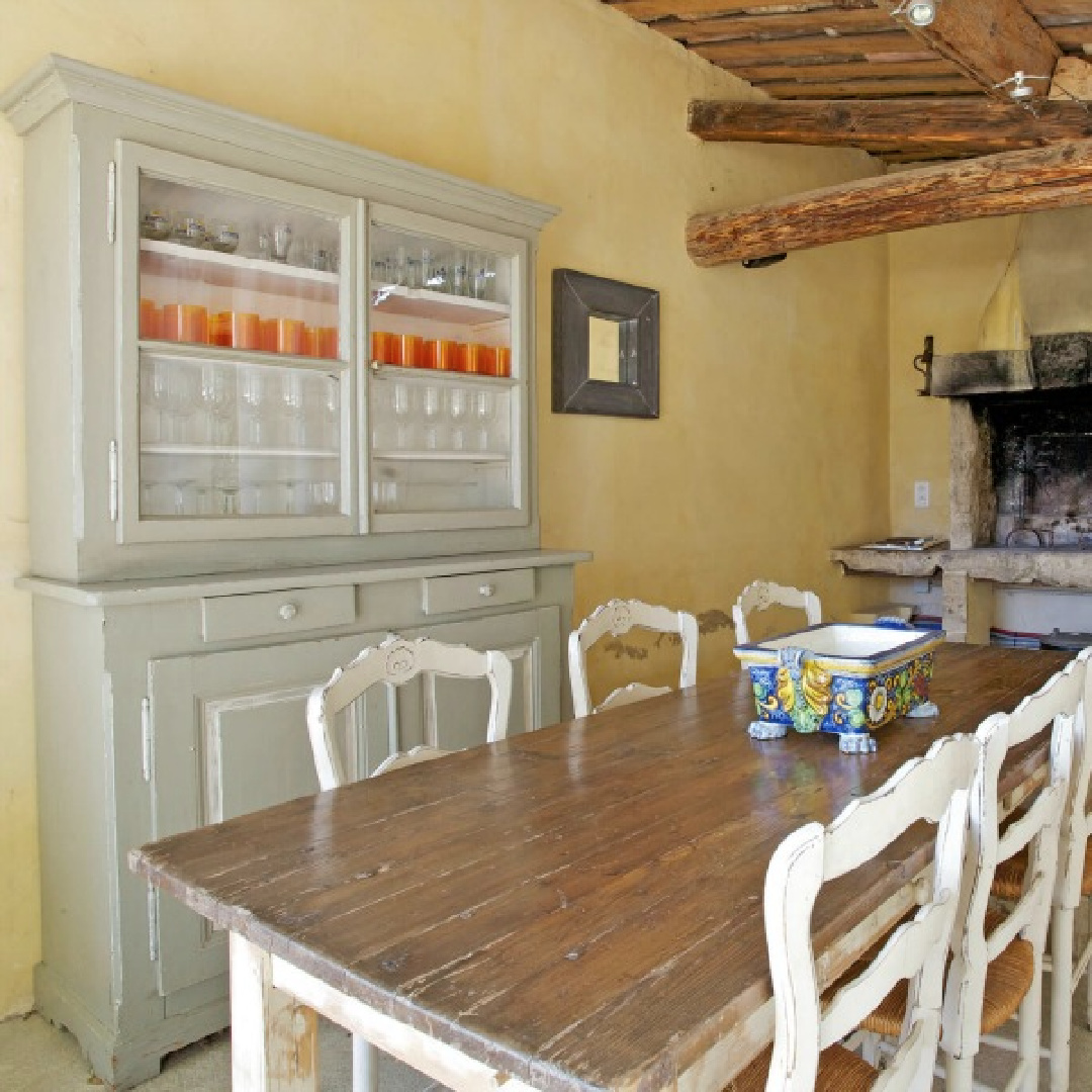 French country farm table and rustic fireplace in a sunny yellow stucco kitchen in Provence - Bonnieux Villa (Your Haven in Paris).