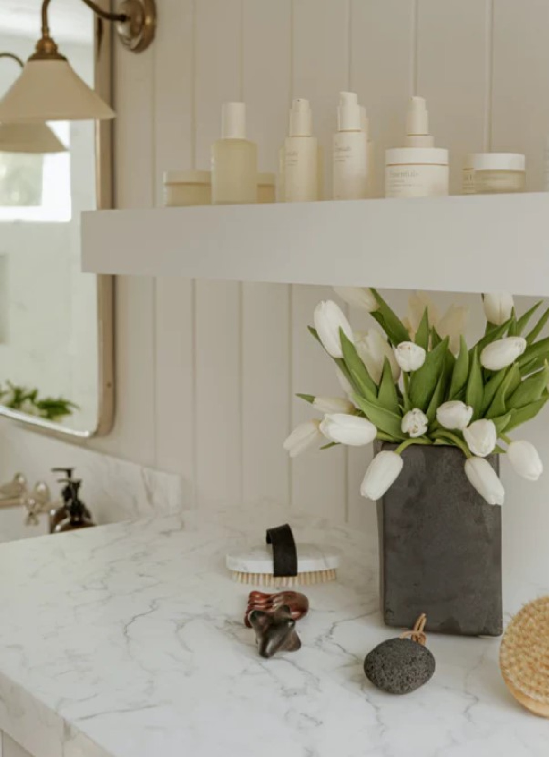 White bath with Jenni Kayne Oak Essentials product on shelf.