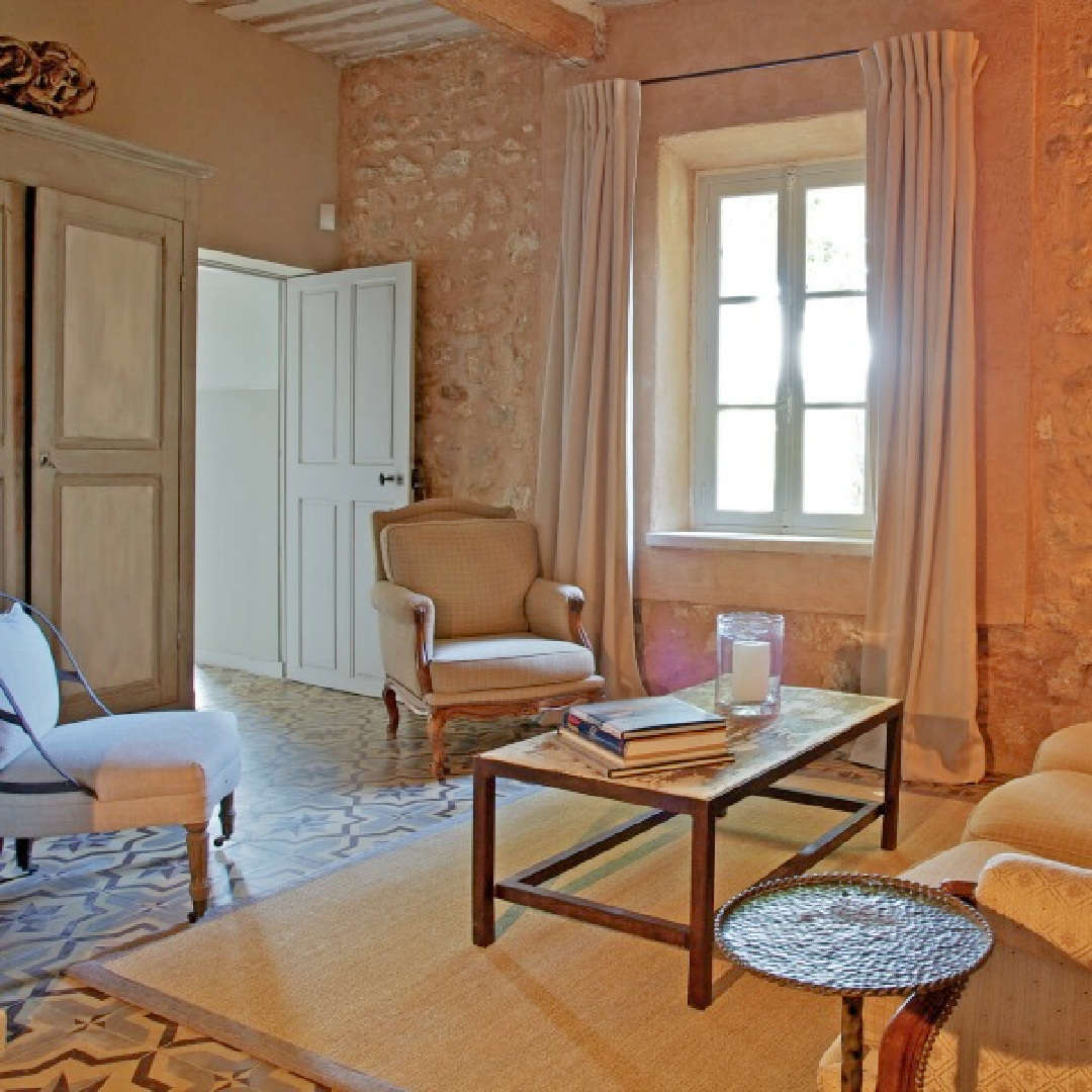 French farmhouse living room with stone walls and patterned tile flooring in Provence's Bonnieux Villa - a vacation rental from Your Haven In Paris.