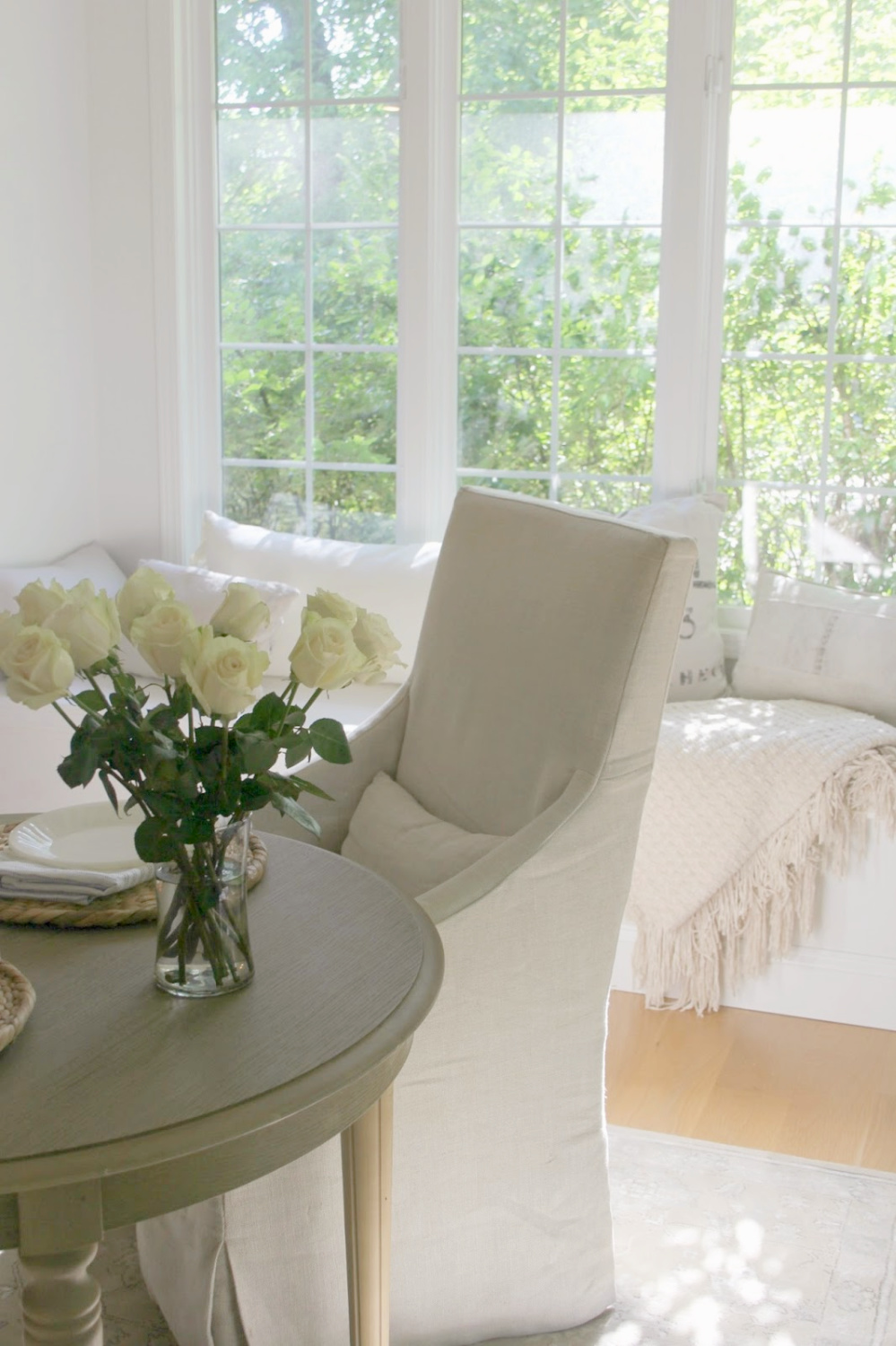 Belgian linen slipcovered slope arm dining chair and window seat in breakfast nook - Hello Lovely Studio.