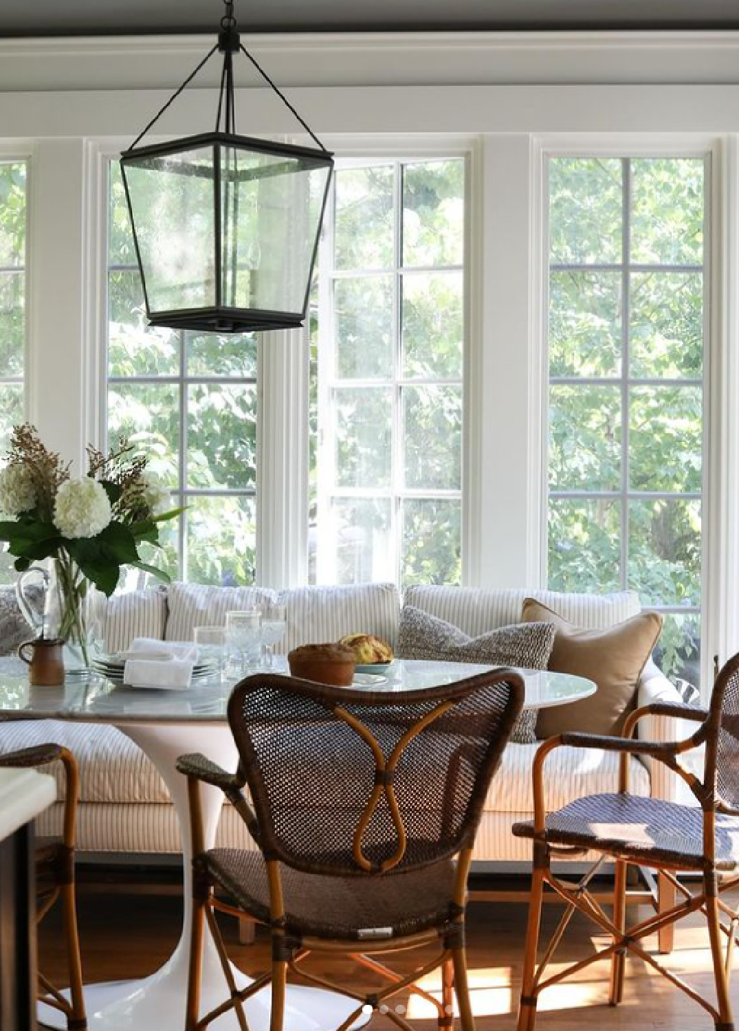 Gorgeous classic breakfast nook with Saarinen style table, sofa, and woven chairs - @parkandoakdesign.