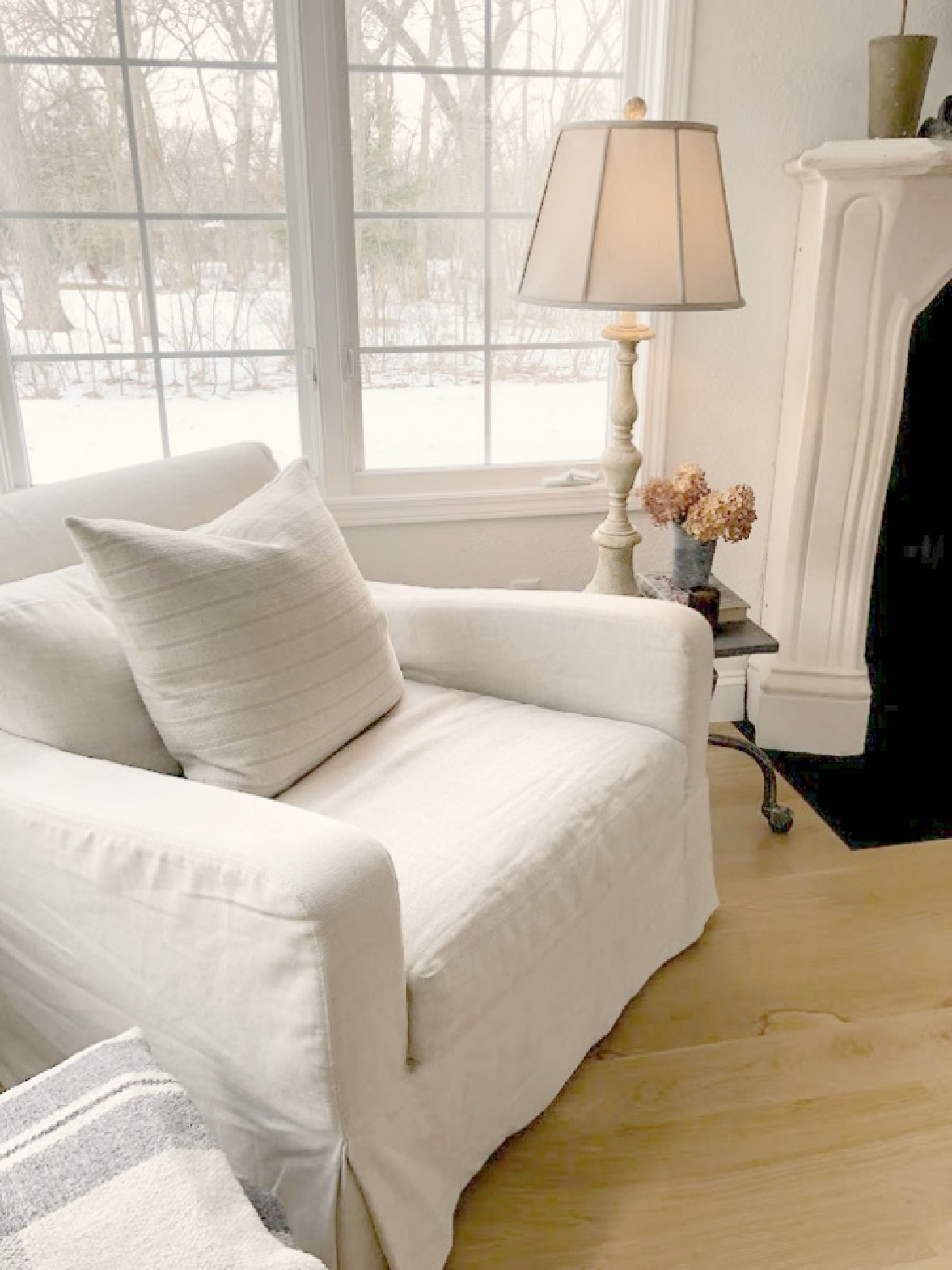 Hello Lovely's white living room with Belgian linen club chair and French fireplace. #modernfrench #belgianstyle #europeancountry