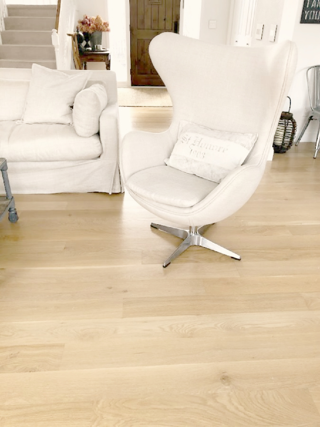 Belgian linen upholstered egg chair and slope arm sofa (RH) with white oak hardwoods in Hello Lovely's living room.