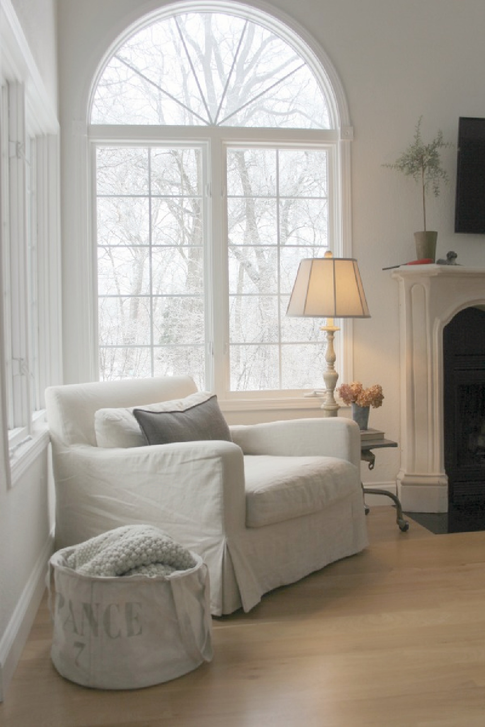 Hello Lovely's modern European country living room with linen club chair, white oak flooring and French stone fireplace. #modernfrench #modernbelgian