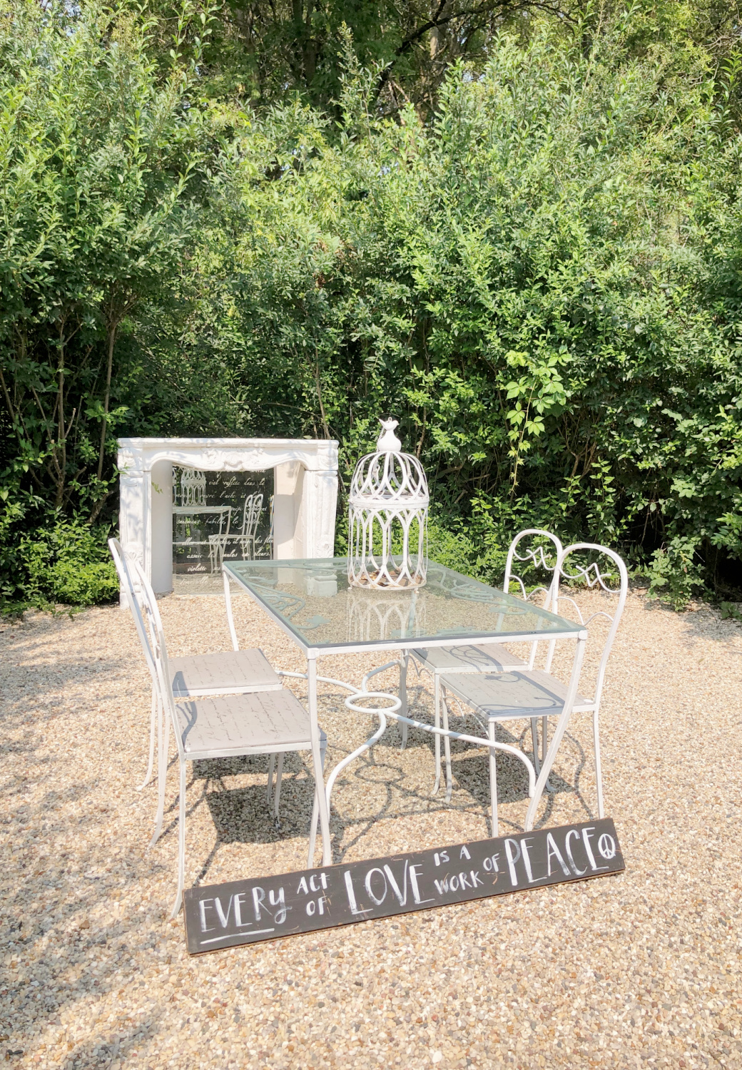 Hello Lovely's secret French courtyard with pea gravel, French fireplace, and vintage dining set. #frenchcountry #frenchcourtyard