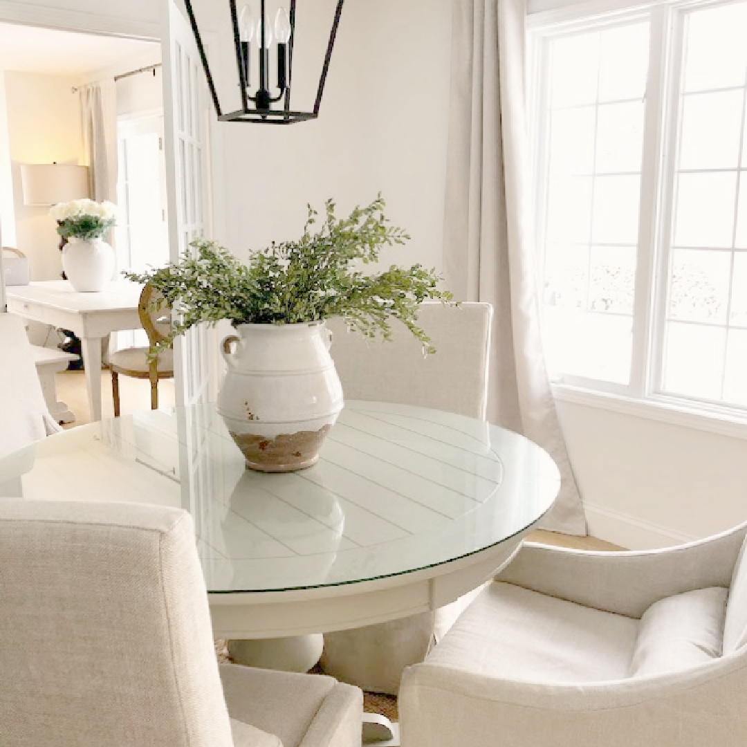 Belgian linen slipcovered dining chairs with round table in modern European country dining room - Hello Lovely Studio.