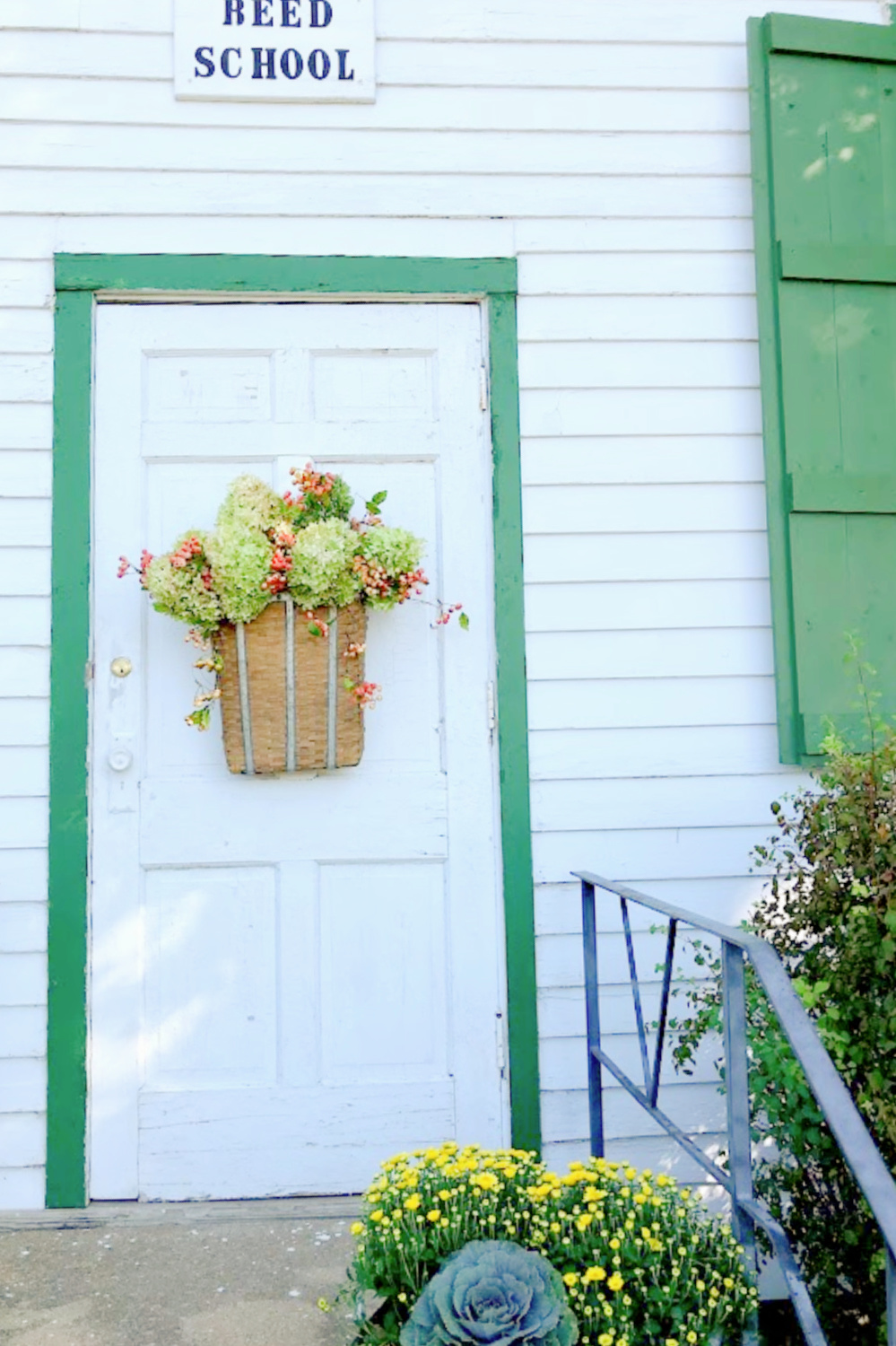 Lovely woven basket with fall floral arrangement with hydrangea and berries on a vintage white door - Hello Lovely Studio. #fallflorals #fallhydrangea #fallporch