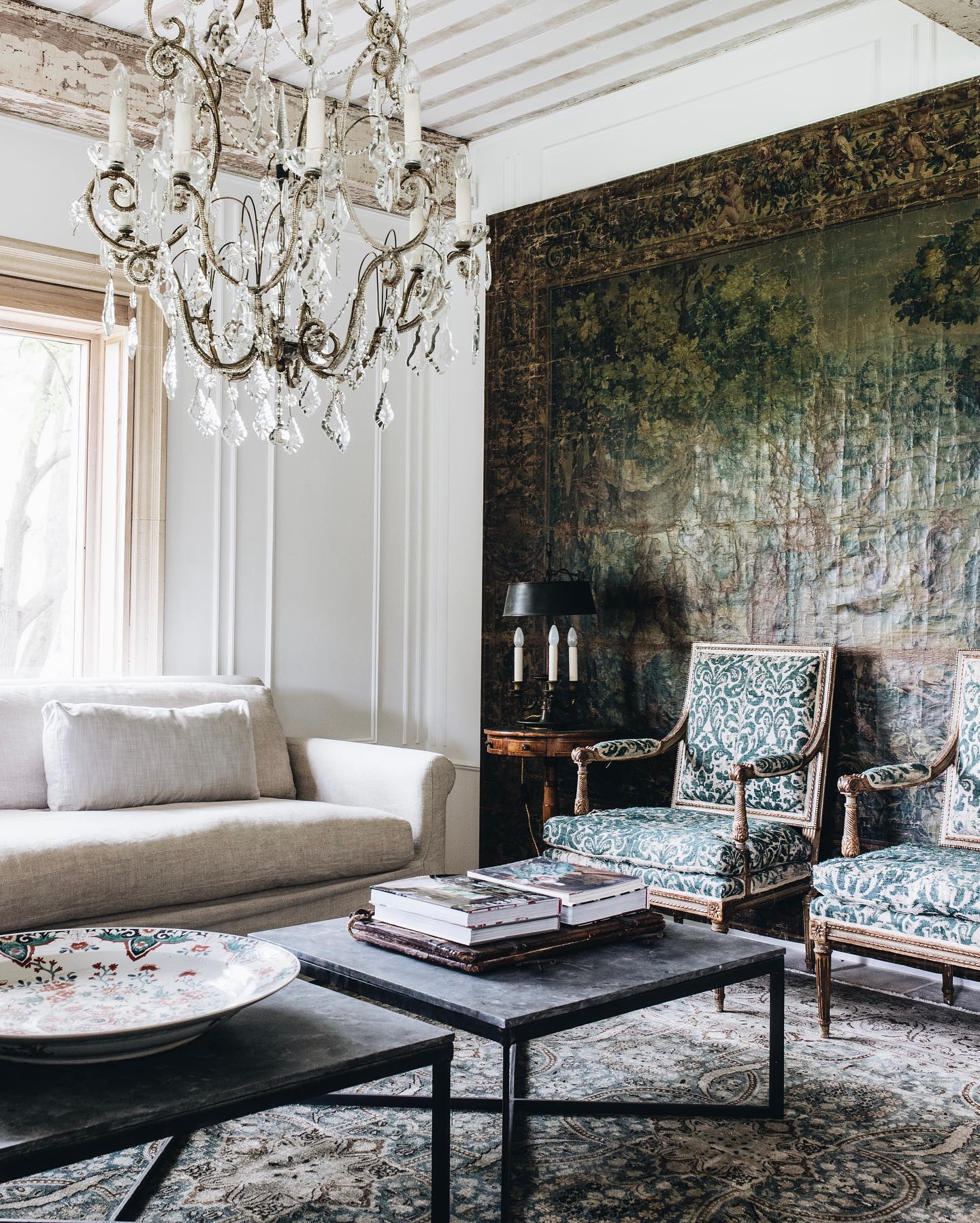 Tapestry on wall and grand crystal chandelier in an elegant interior in Meliss Penfold's Living Well By Design (photo: Abbie Melle). #timelesslivingroom #antiquetapestry